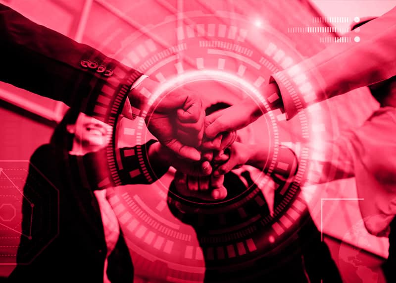 Group of people clenching their fists and bumping them together while smiling, with a technology-themed circle in the center, symbolizing teamwork and collaboration in technology